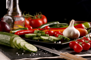 Healthy food. Vegetables on a black plate and stone cutting board and wooden background.