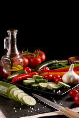 Healthy food. Vegetables on a black plate and stone cutting board and wooden background.