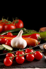 Healthy food. Vegetables on a black plate and stone cutting board and wooden background.