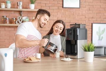 Young couple using coffee machine in kitchen