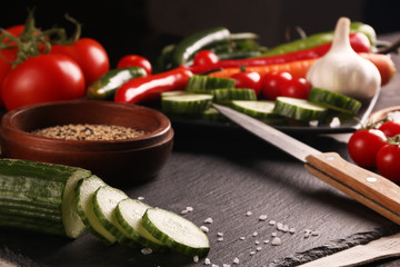 Healthy food. Vegetables on a black plate and stone cutting board and wooden background.