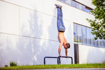 Workout in summer: Young fit Caucasian man is doing a handstand