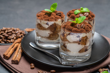 Classic tiramisu dessert in a glass on dark concrete background