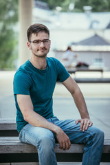 Male employee is sitting outdoors, portrait shot, urban business scene.