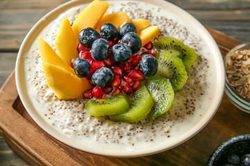 Bowl with tasty chia dessert on wooden board