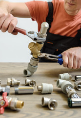 The worker is connecting elements of the plumbing.