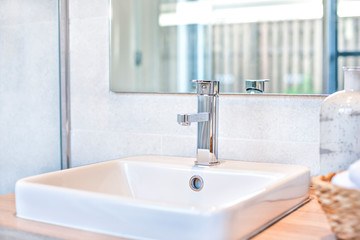 Silver tap and white sink close up beside a mirror