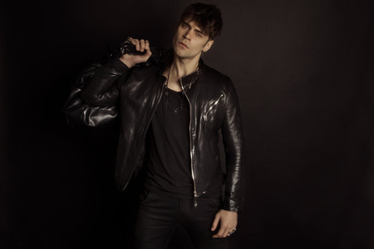 Strong stripped muscle male model in casual look in black shirt and leather jacket on black isolated font background