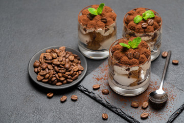 Classic tiramisu dessert in a glass on stone serving board on dark concrete background