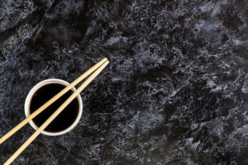 Japanese sushi chopsticks and soy sauce on black background. Top view with copyspace