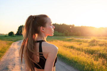 Running concept for exercising, fitness and healthy lifestyle. Young girl in a black top straightening long, beautiful hair before jogging in the forest