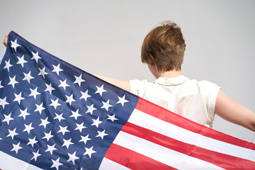 Redhead caucasian girl holds usa flag behind her back