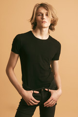 Muscle blonde beautiful stripped male model with long hair in black casual look on beige brown...