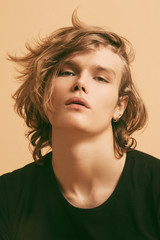 Muscle blonde beautiful stripped male model with long hair in black casual look on beige brown...