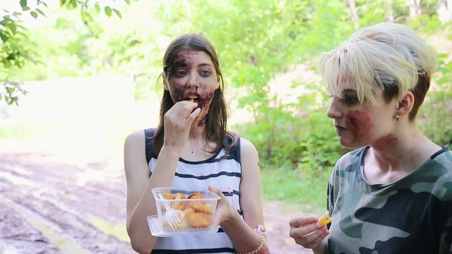 Backstage of the zombie apocalypse shooting. Zombies eating fries and a makeup artist applying makeup for the survivor man