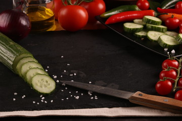 Healthy food. Vegetables on a black plate and stone cutting board and wooden background. Copy space