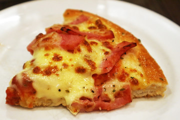 Piece of Bacon and Cheese Pizza on White Plate
