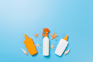 sunscreen cream with starfish and seashells in bottles on blue background, top view