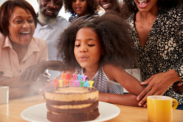 Multi-Generation Family Celebrating Granddaughters Birthday At Home With Cake And Candles