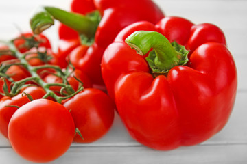 Ripe red peppers with tomatoes on white table