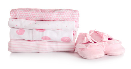 Stack of baby clothes and shoes on white background