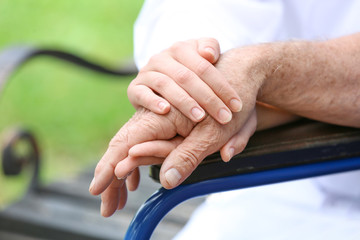 Elderly man with caregiver in park, closeup