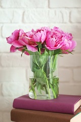 Vase with beautiful peony flowers and books on white background