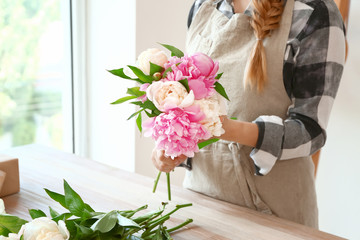 Female florist with beautiful bouquet of peonies in shop