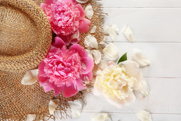 Hat with peonies on white wooden background