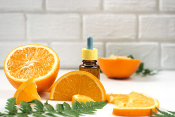 Vitamin C and Mesotherapy. Serum with vitamin C in brown glass bottles, leaf fern and orange in a...