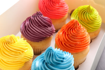 Many tasty colorful cupcakes in box