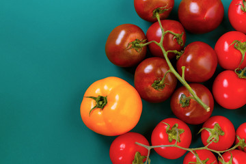 Top view of a diverse red, yellow, black tomatoes, isolaetd on an green dark background.