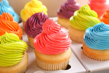 Many tasty colorful cupcakes in box