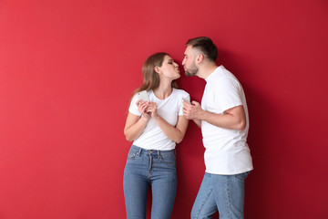 Portrait of happy young couple with mobile phones on color background