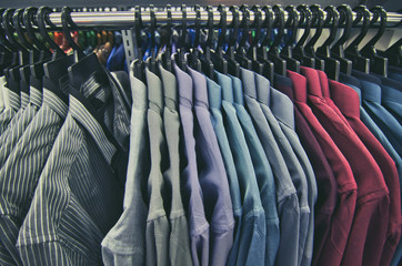 Colorful selection of clothes for men hanging on hangers in shopping mall for store sale concept