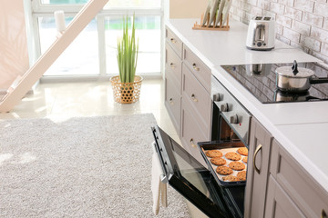 Open oven with tasty homemade cookies in kitchen