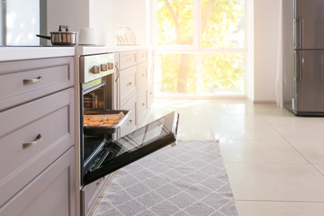 Open oven with tasty homemade cookies in kitchen