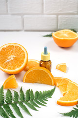 Natural cosmetic skincare. Serum with vitamin C in brown glass bottles, leaf fern and orange in a cut. High dose vitamin c synthetic for skin. Organic Natural Cosmetics Concept