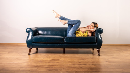 A woman listening to music while posing on a sofa