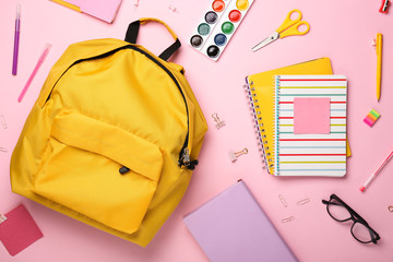 School backpack and stationery on color background