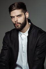 Muscle strong bearded face beautiful stripped male model in formal look with shirt and suit on grey isolated font background