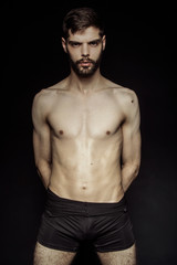 Fototapeta na wymiar Muscle strong bearded face beautiful stripped male model in black underwear on black isolated font background