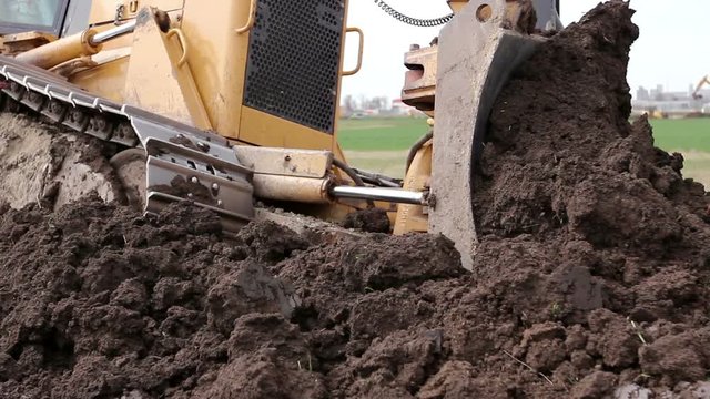 Close up view on bulldozer's undercarriage during pushing ground at construction site.
