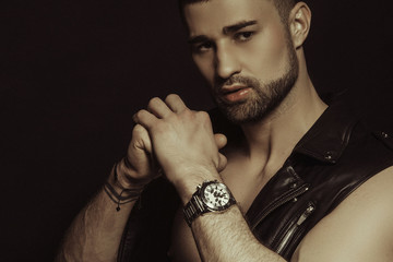 Muscle strong beautiful stripped male model in black leather jacket and underwear on black isolated font background