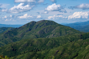 Natural landscape. Beautiful cumulus clouds float above a mountain valley.