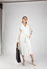 Asian Chinese Fashion influencer modeling in white dress with a tote bag isolated in white...