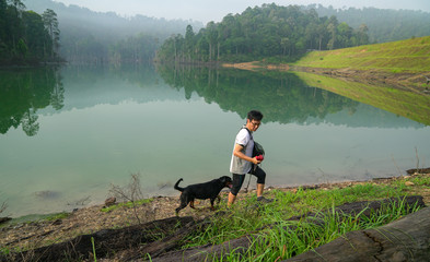 Dog and man hiking in the forest with lake