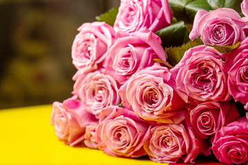 pink roses on yellow table, background blurred