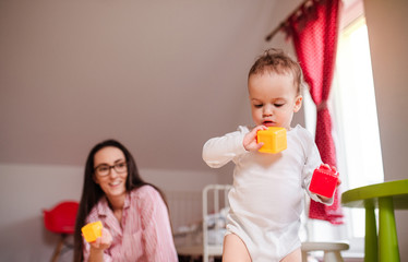 Young mother with small toddler son indoors at home, playing.