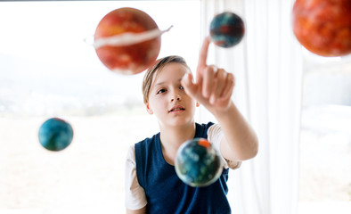 A small boy with model of solar system indoors.